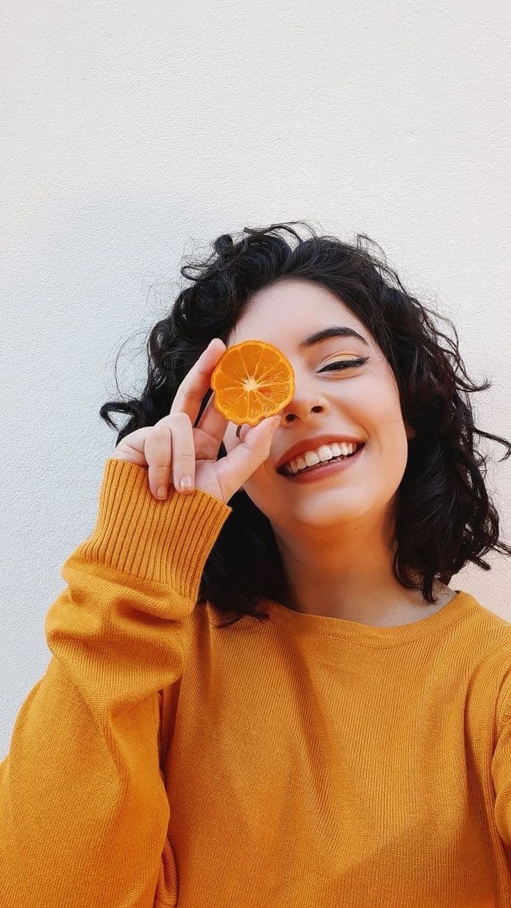 Woman with glowing skin holding orange slice